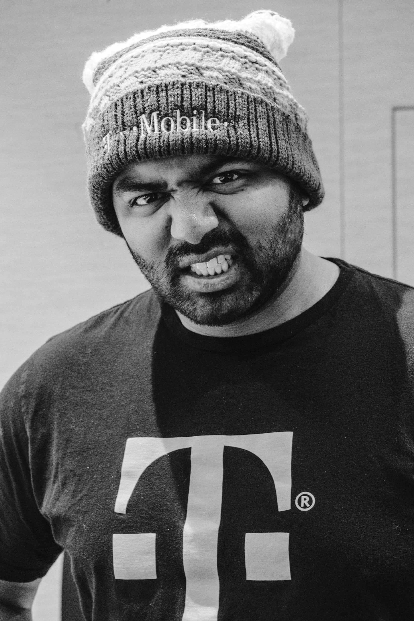 Photograph of a Man growling, wearing a T-Mobile hat and T-Shirt