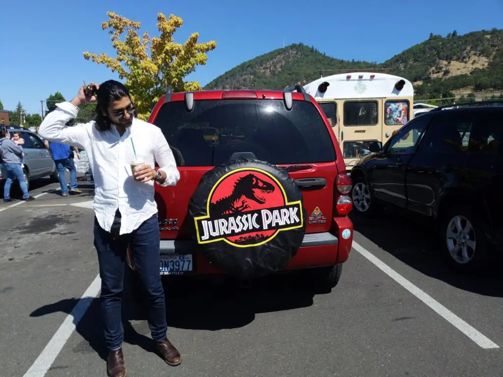 Sanwal Deen standing in front of a red Jeep Liberty 2005 with a Jurassic Park Tire cover