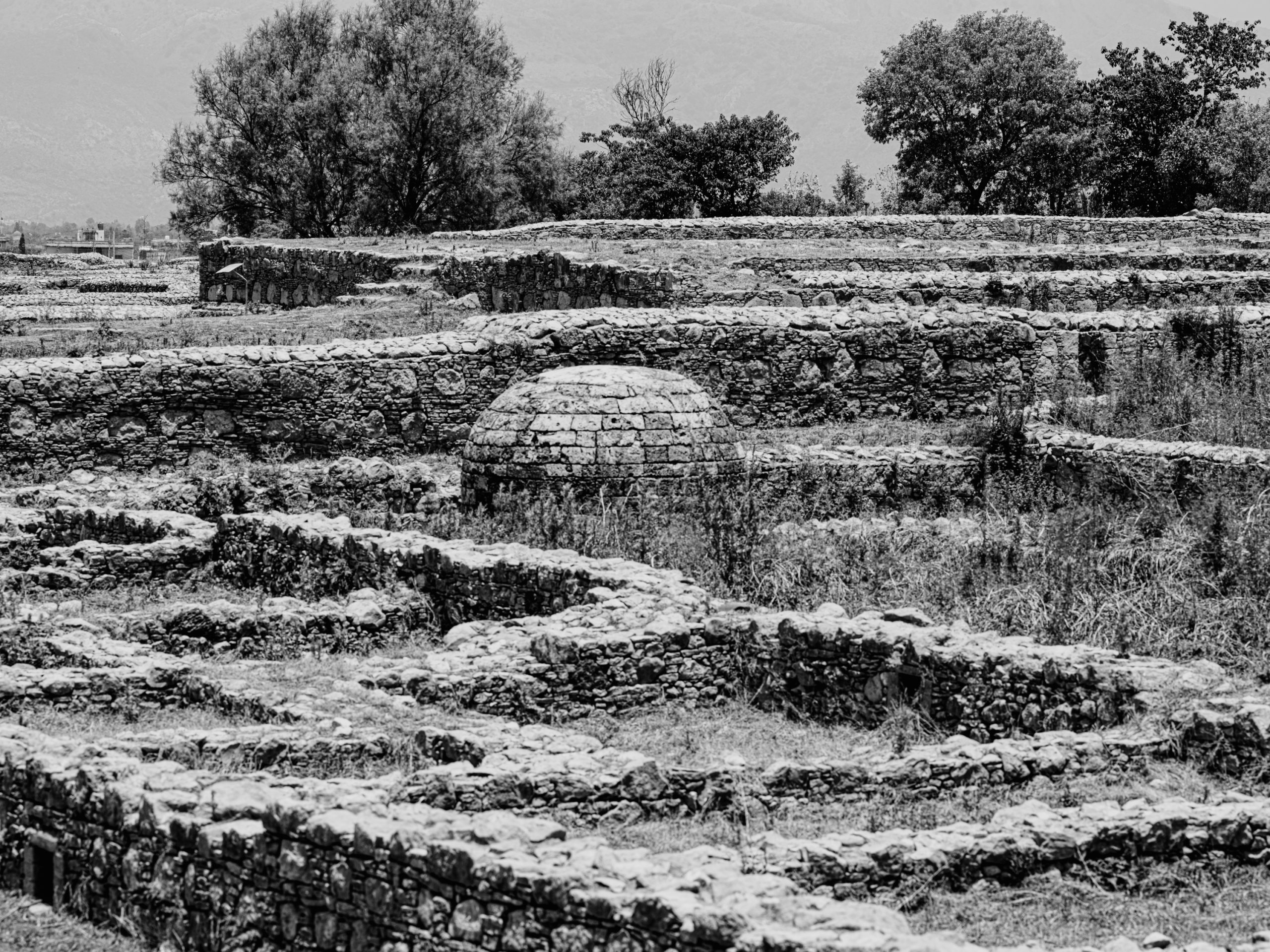 A black and white photograph of a Stupa at the ancient city of Sirkap, Pakistan