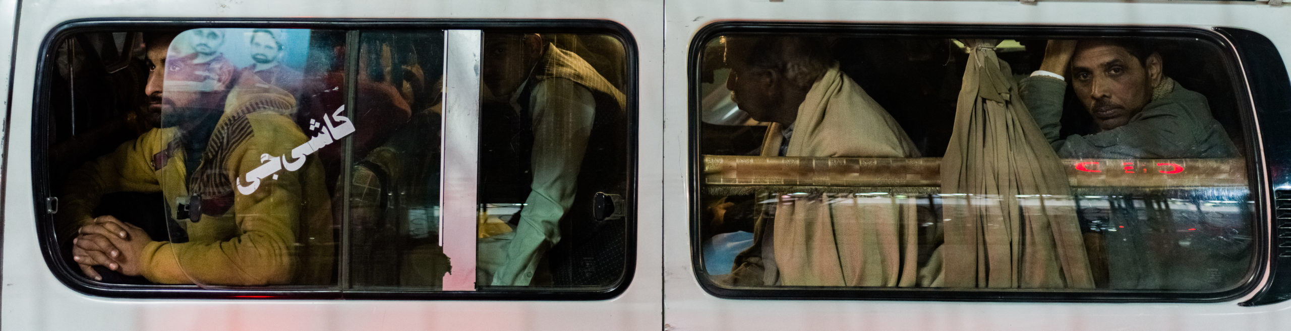 People crammed in a commuter white van peer through the window