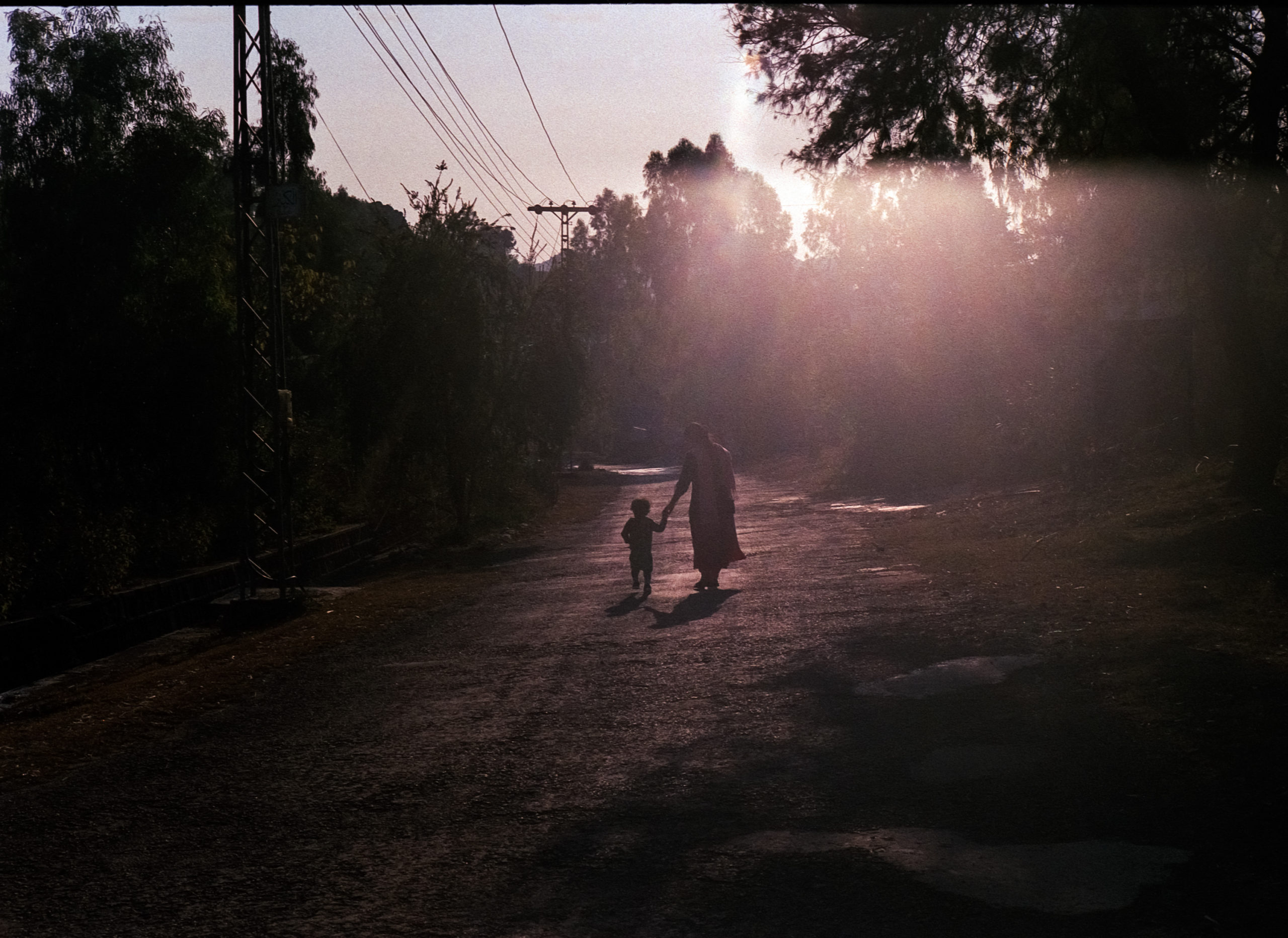 Sillhoutte of a girl and a boy walking into the sunset.