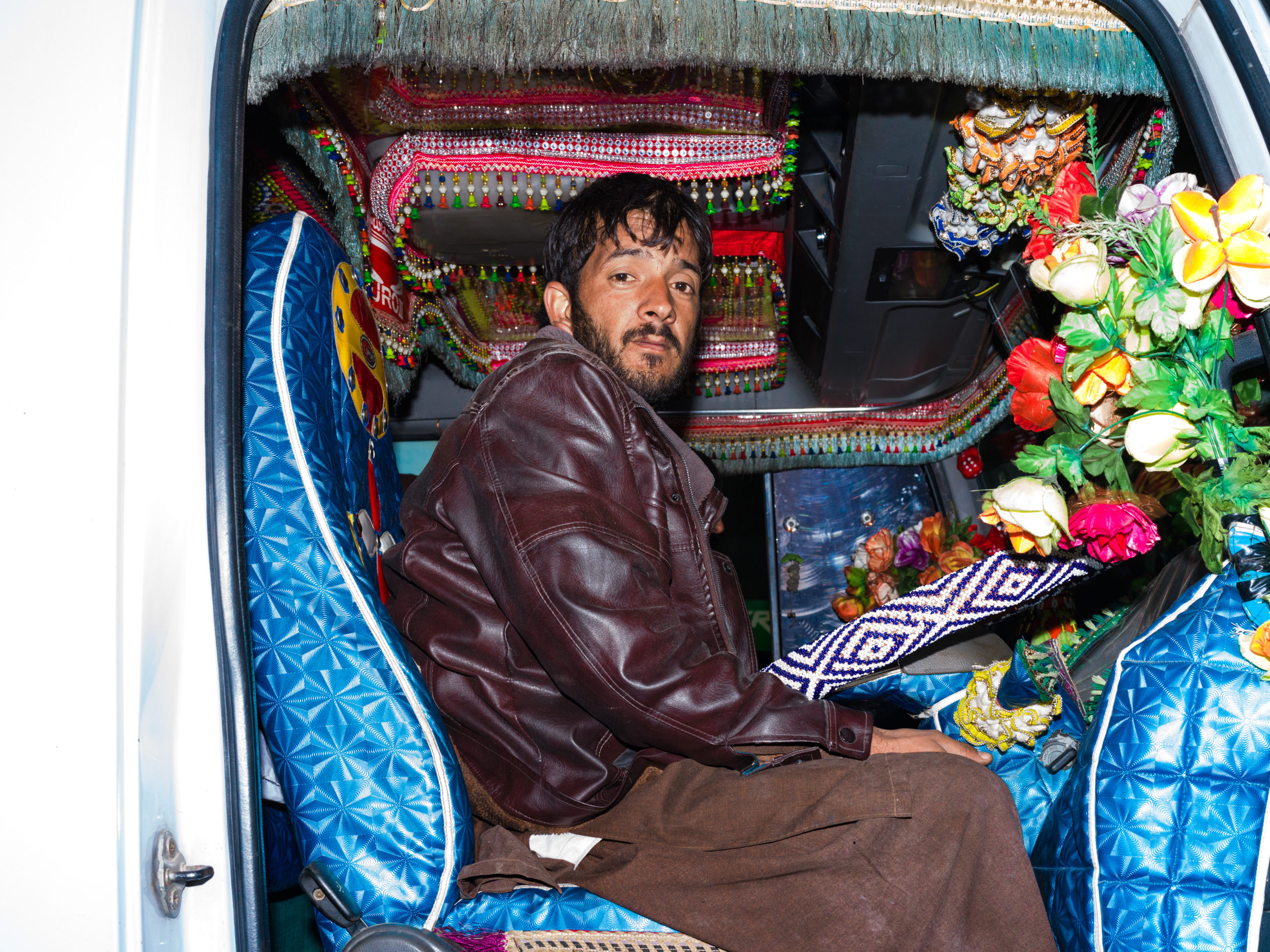 A truck driver poses for a photo inside his decorated truck