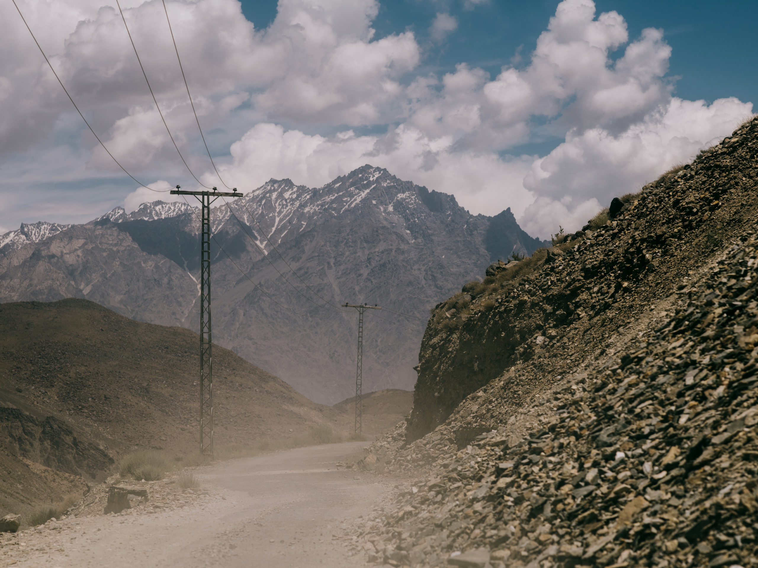 A dusty road with the mountains in the background