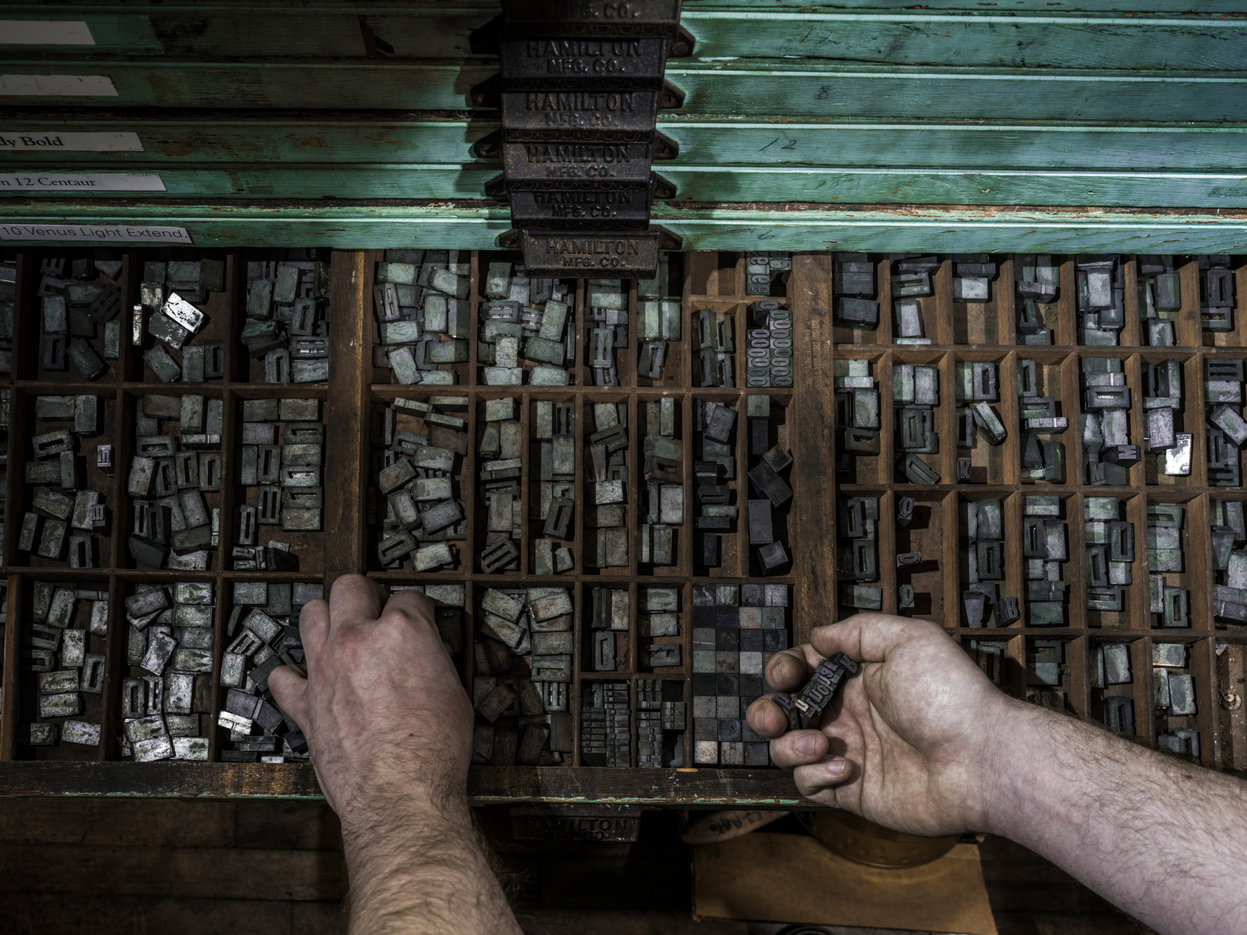 A typesetter selects fonts from his drawers