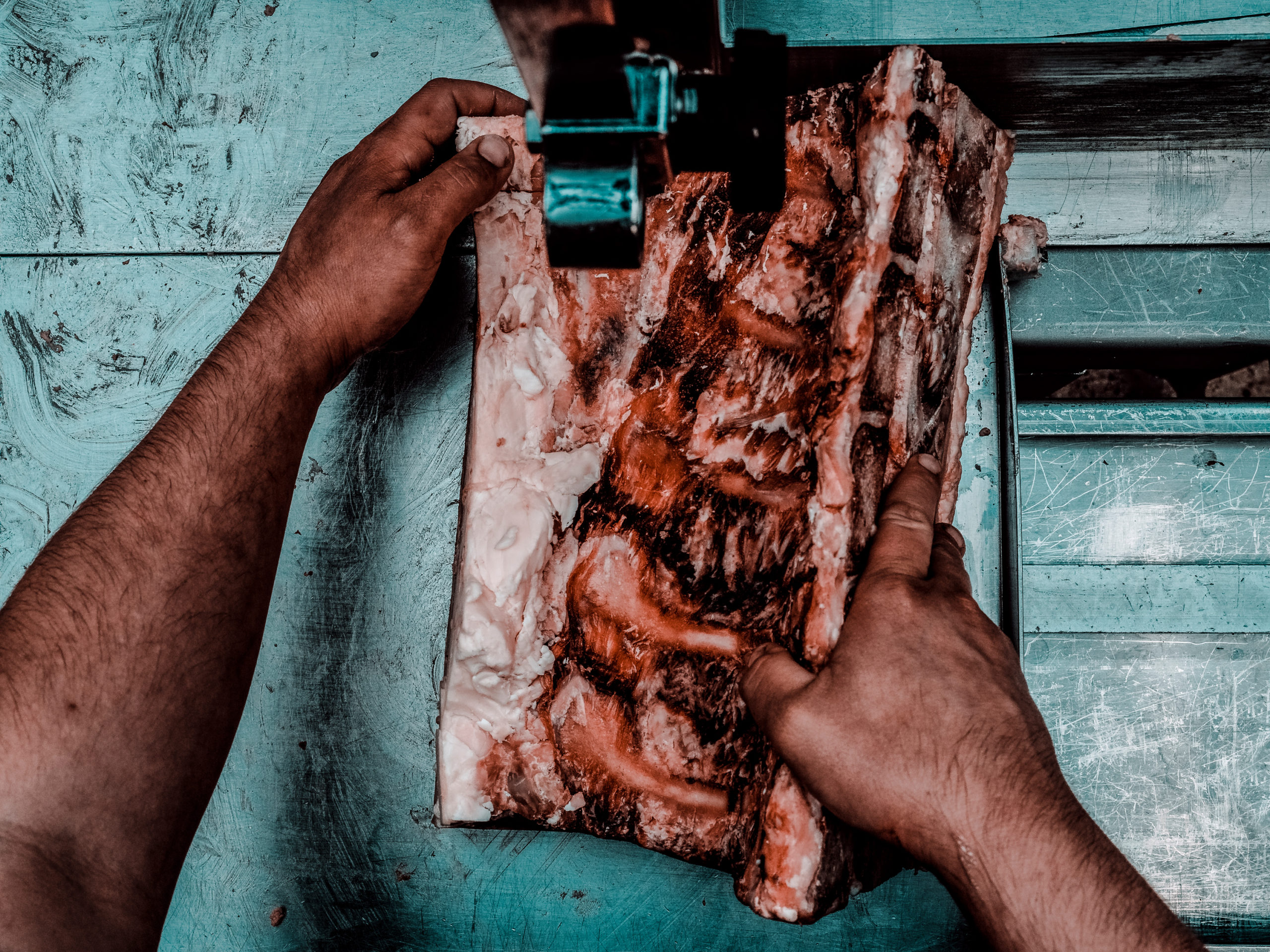 A butcher using a machine to saw through meat