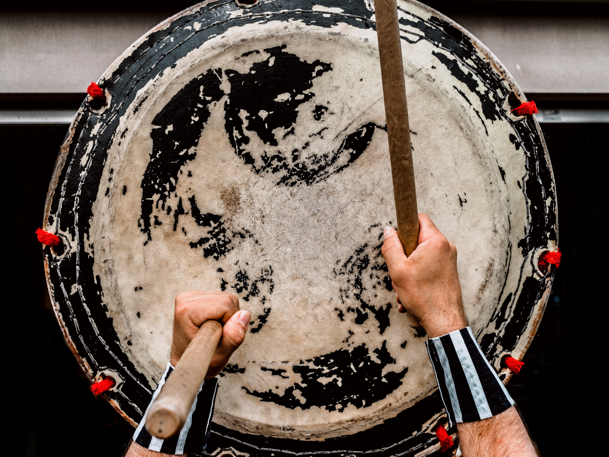 Showing hands of a taiko player beating drum sticks on his taiko drum