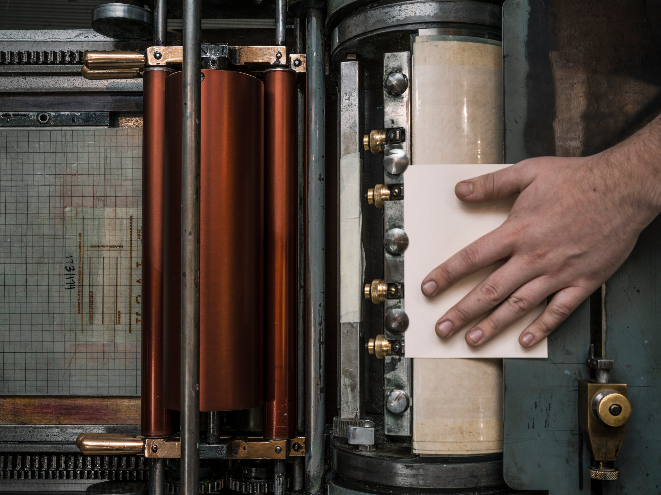 A letterpress artist passes a print through a machine